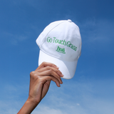 Photo of HUA's Go Touch Grass hat held against the sky