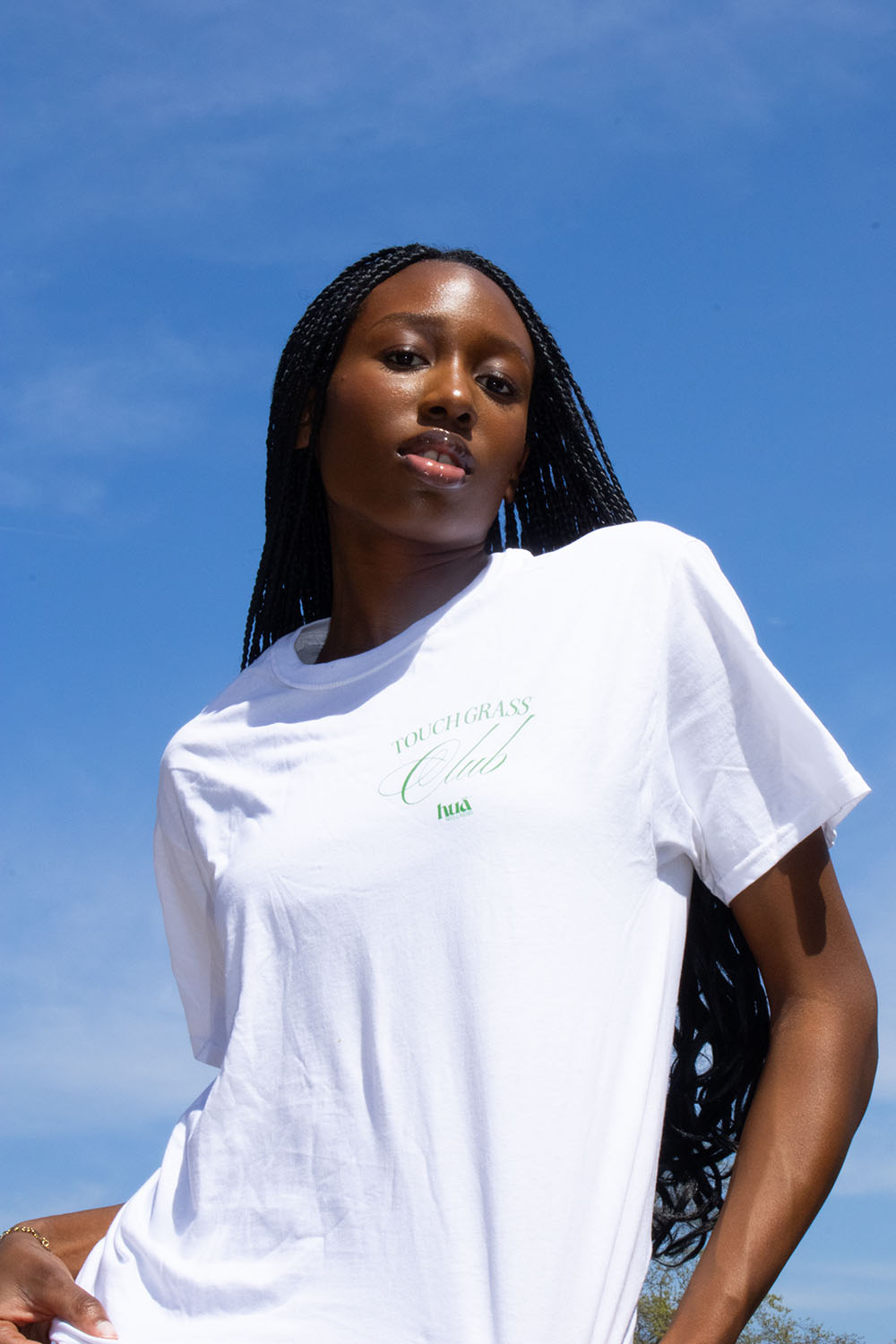 Model wearing Touch Grass Club t-shirt against blue sky